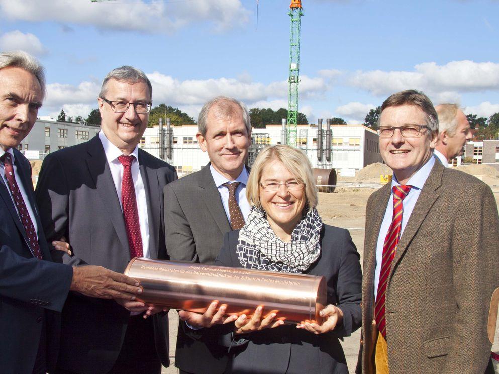 Sie versenkten die mit Tageszeitung und Urkunde bestückte Zeitkapsel auf dem Baufeld in Lübeck (v.l.): Dipl.-Ing. Alexander Naujoks, Vorstandsvorsitzender BAM Deutschland AG, Mag. Gottfried Koos, Mitglied Vorstand VAMED AG Wien, Prof. Dr. Jens Scholz, Vorstandsvorsitzender UKSH, Kristin Alheit, Ministerin für Soziales, Gesundheit, Wissenschaft und Gleichstellung und Lübecks Innensenator Bernd Möller.