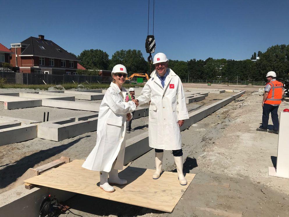 Wethouder Marloes Borsboom van de gemeente Rijswijk en Wilco van de Ban, directeur AM Zuidwest, leggen samen symbolisch de eerste funderingsbalk tijdens een feestelijke bijeenkomst ter gelegenheid van het startsein bouw op maandag 2 juli.