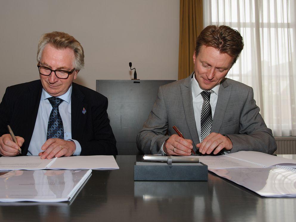 Burgemeester Geert van Rumund (links) en Michiel Terpstra (vestigingsleider BAM Gebouwservices Arnhem) ondertekenen de overeenkomst voor de vernieuwbouw van het stadhuis.